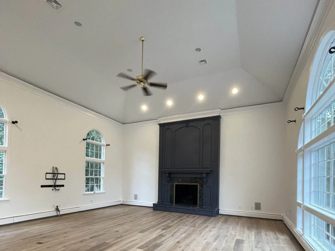 The same great room after painting, with the fireplace surround in navy and walls and ceiling freshly finished
