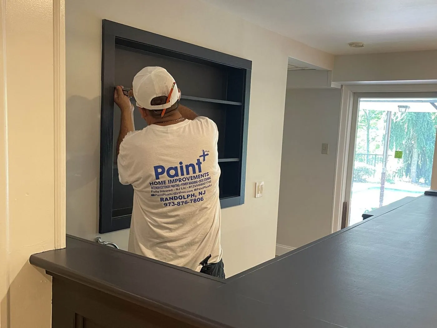 Paint Plus carpenter fitting built-in shelving into a recessed wall behind a new lower-level bar