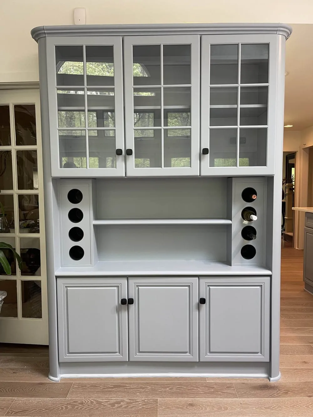 Gray built-in hutch with glass-front upper cabinets and built-in wine bottle storage