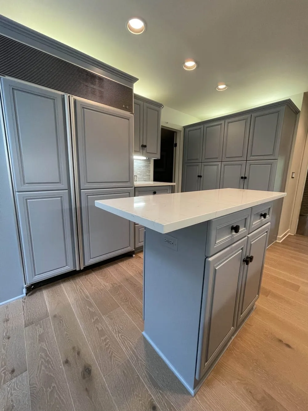 Gray kitchen with double wall ovens, a white-topped island and a mosaic tile backsplash