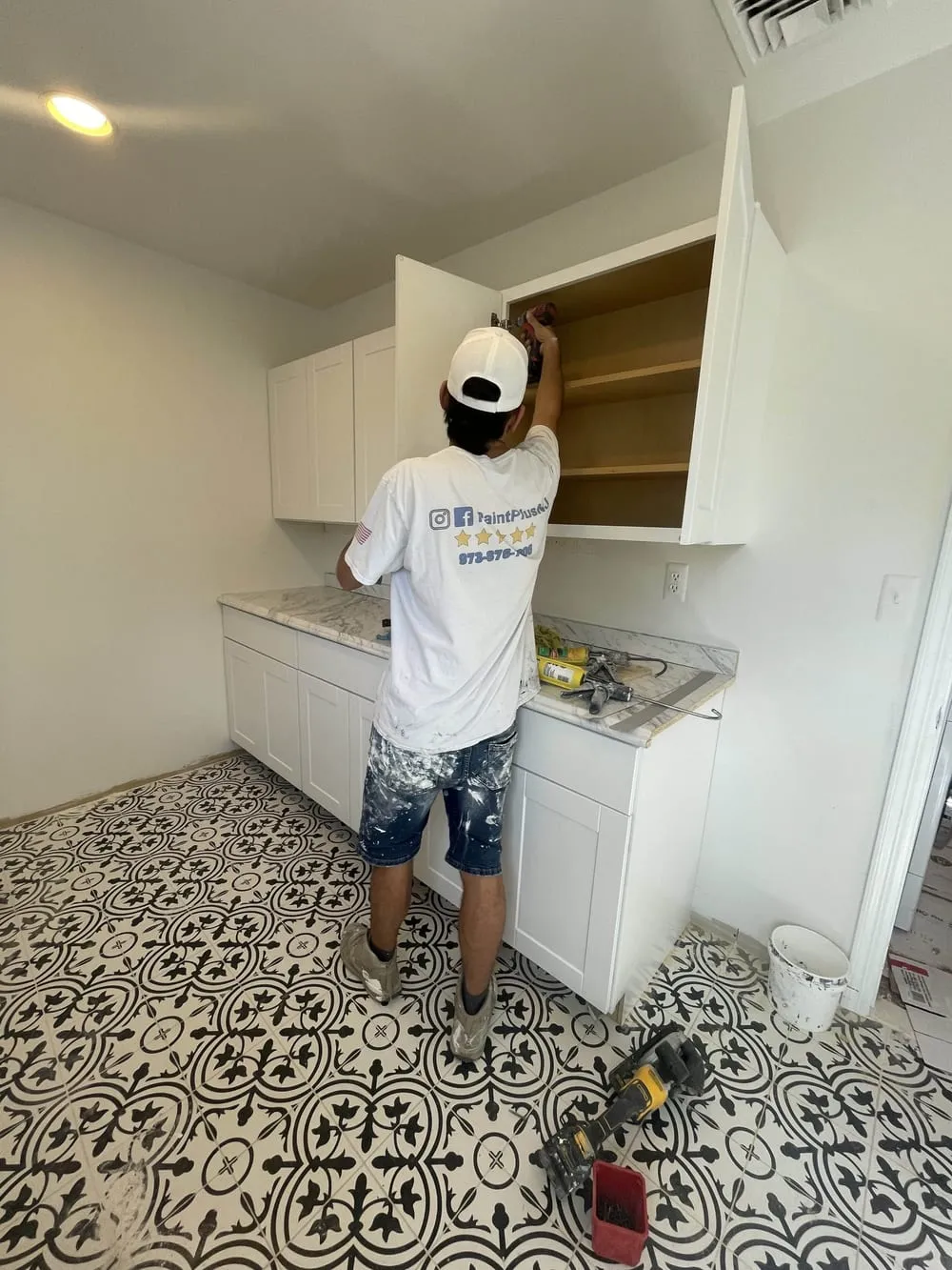Paint Plus crew member hanging white wall cabinets in a laundry room