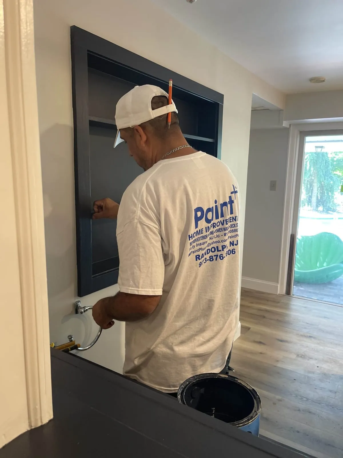 Paint Plus carpenter fitting a navy built-in shelving unit into a recessed wall behind a home bar