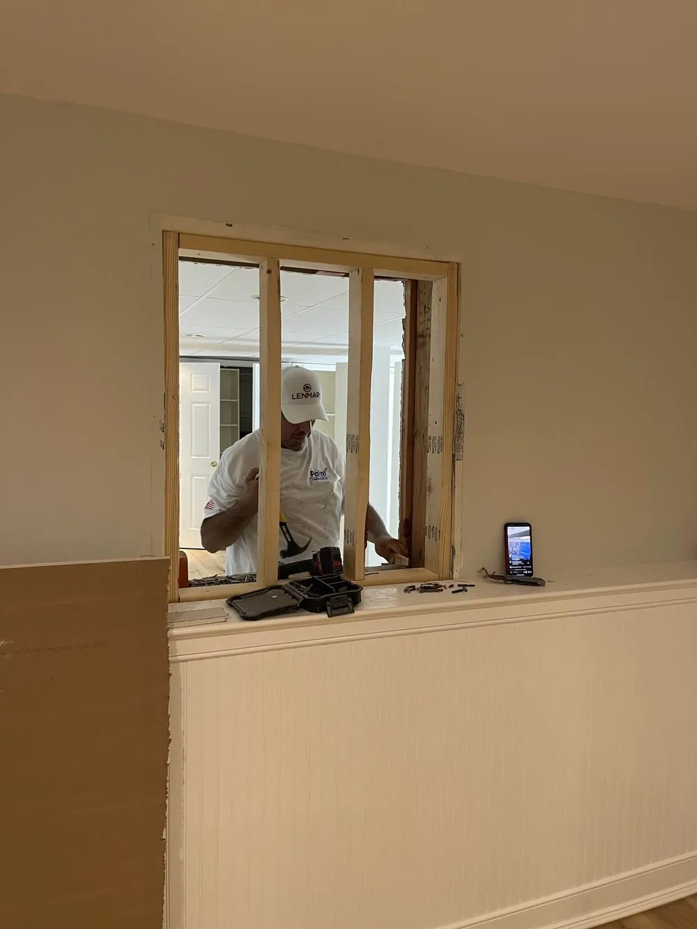 Newly framed interior window opening above a wainscoted wall