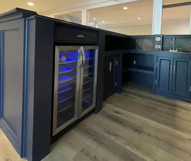 Finished basement with a custom navy bar, a built-in wine fridge and new flooring