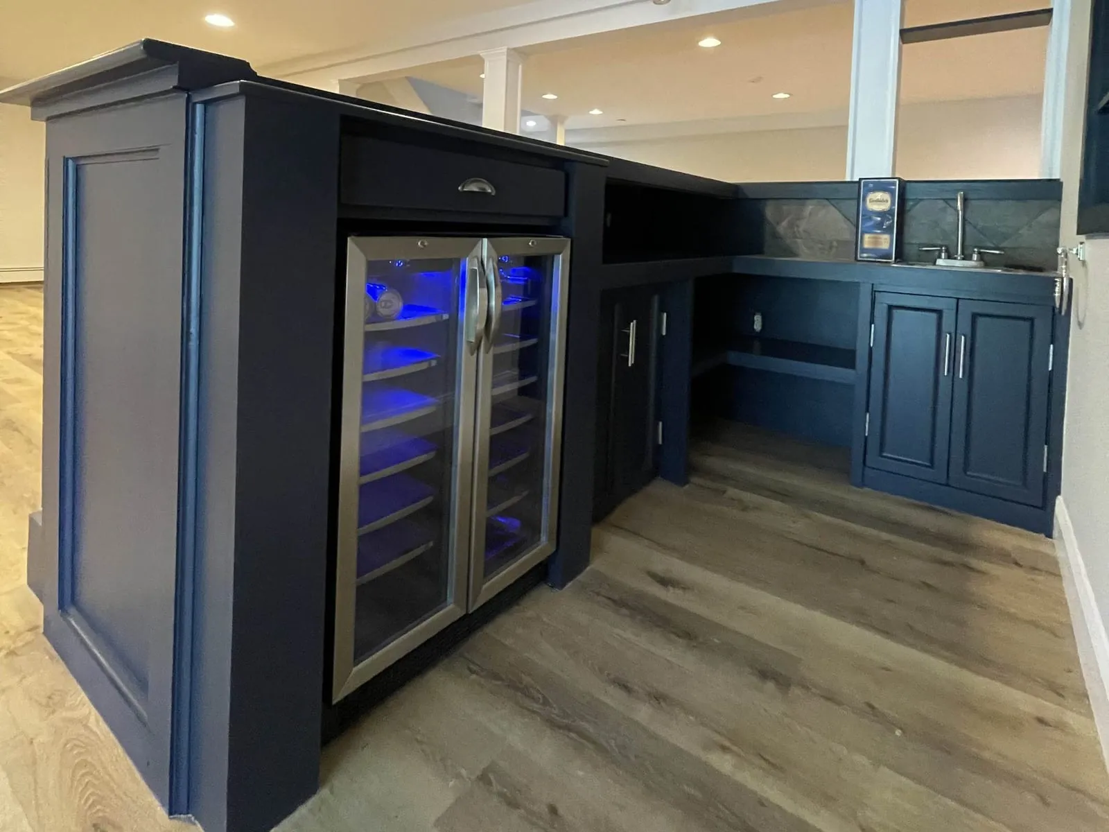Finished basement with a custom navy bar, a built-in wine fridge and new flooring