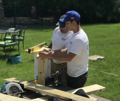 Paint Plus owner John Reyes and a crew member leveling a post while building a deck