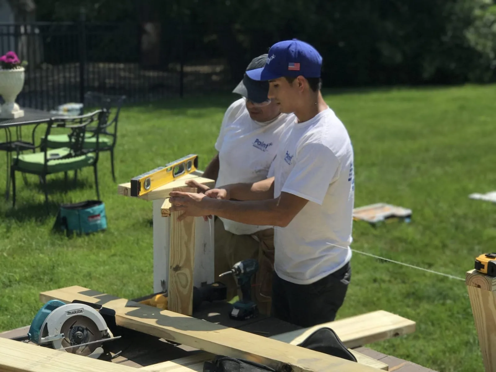 Paint Plus owner John Reyes and a crew member leveling a post while building a deck