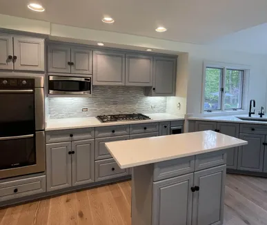 Remodeled kitchen with gray cabinets, a white island and wide-plank wood floors