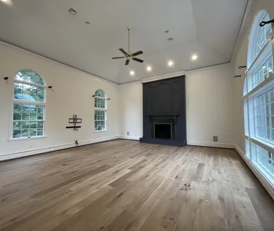 Vaulted great room painted by Paint Plus, with fresh white walls and ceiling and a navy painted fireplace surround