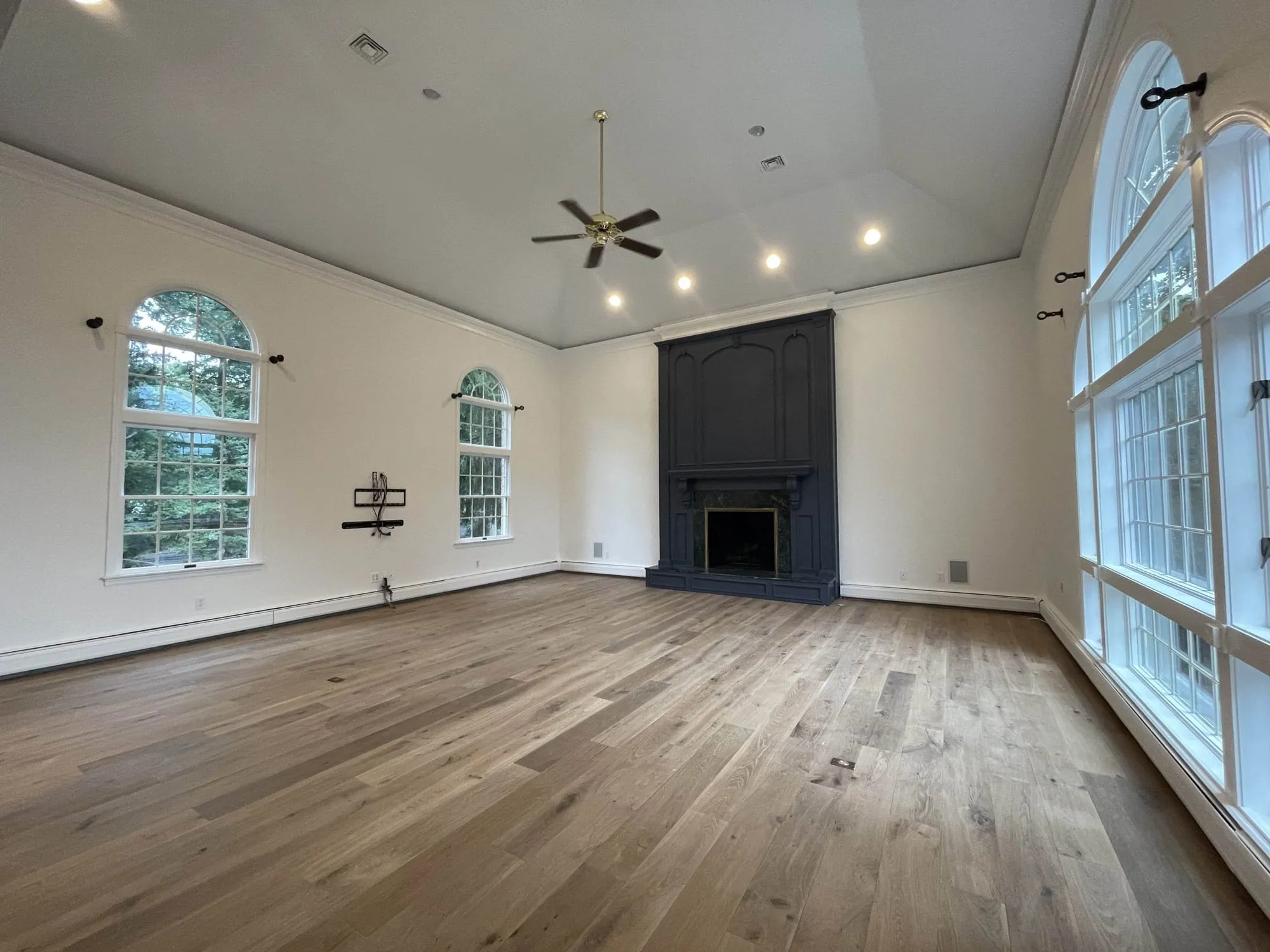 Vaulted great room painted by Paint Plus, with fresh white walls and ceiling and a navy painted fireplace surround