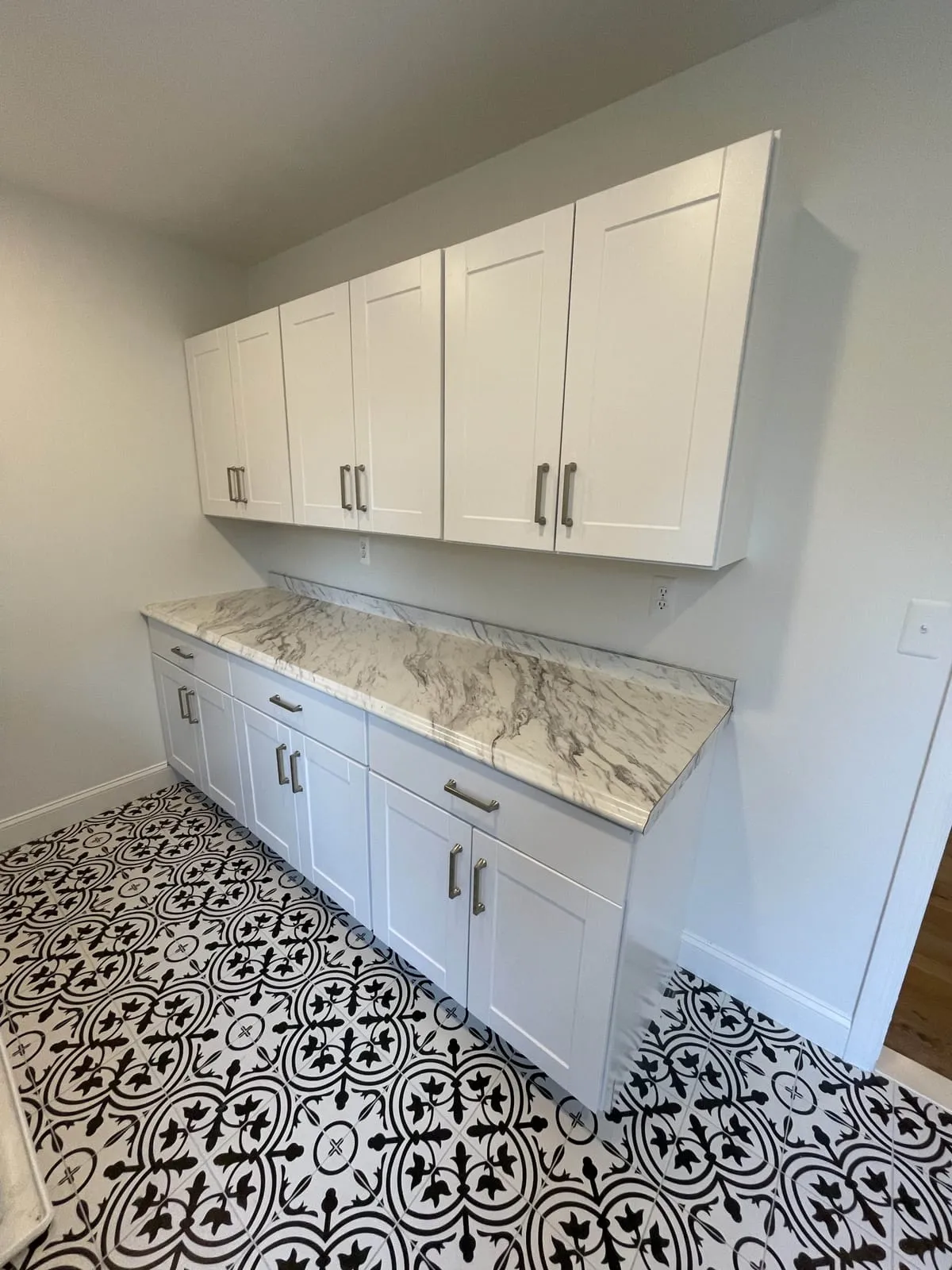 Laundry room with new white shaker cabinets, a stone counter and a patterned tile floor, by Paint Plus