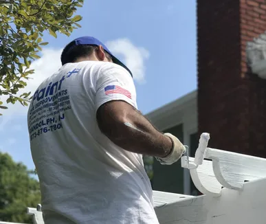 Paint Plus painter painting the white trim of an outdoor pergola