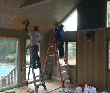 Two Paint Plus painters on ladders painting a vaulted wood plank ceiling in Basking Ridge, NJ