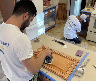 Paint Plus crew sanding kitchen cabinet doors before refinishing in Bedminster, NJ