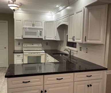 White painted kitchen cabinets with dark granite counters, refinished by Paint Plus in Denville, NJ