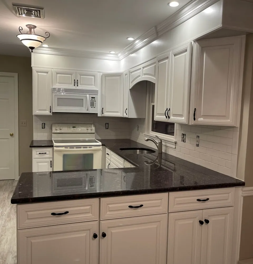 White painted kitchen cabinets with dark granite counters, refinished by Paint Plus in Denville, NJ