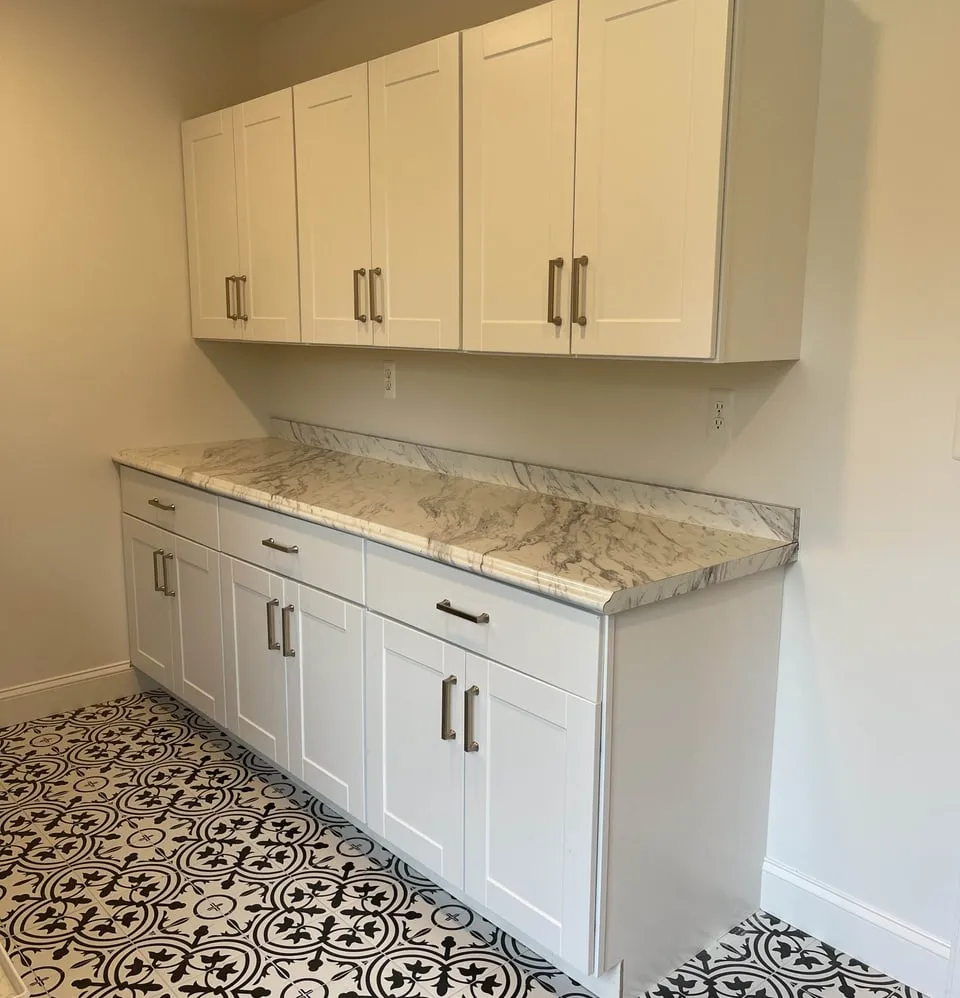 White shaker cabinets and marble-look counters in a remodeled laundry room by Paint Plus in Mountain Lakes, NJ