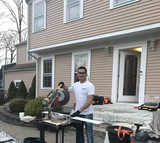 Paint Plus owner John Reyes cutting trim with a miter saw outside a client’s home